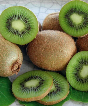Hayward fuzzy kiwi | Actinidia deliciosa hayward Hayward Fuzzy Kiwi fruits cut in half to reveal green flesh with black seeds.