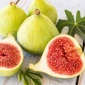 Four yellowish green Desert King Fig Tree fruits, with one fruit cut open to reveal purplish red flesh.
