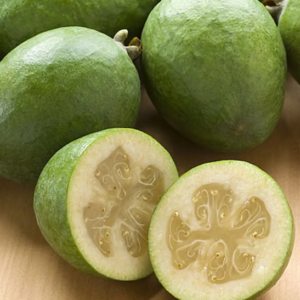 A group of Takaka Pineapple Guava plant green fruits, with one cut in half revealing a creamy centre.