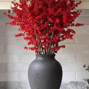 Gorgeous Winter red winterberry holly stems in a dark ceramic vase.